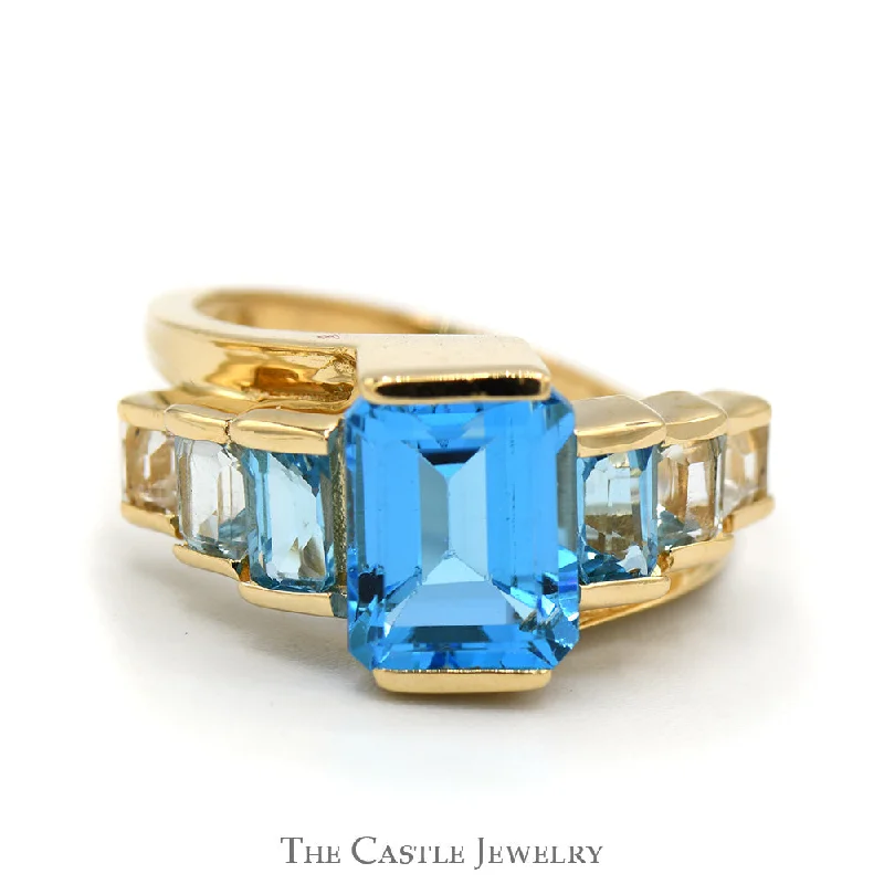 ladies rings with ruby red -Emerald Cut Blue Topaz Ring with Graduated Design in 14k Yellow Gold Bypass Setting